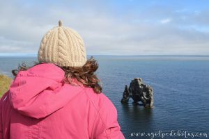 Mujer mirando Hvitsekur, el troll petrificado. Una famosa formación rocosa de Islandia