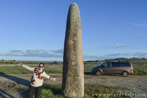 Mujer posando junto a su furgoneta camper en un dolmen prehistórico del Alentejo