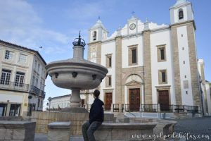Persona sentada en una fuente admirando la arquitectura de Évora