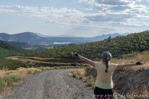 Mujer de espaldas con el embalse del Atazar al fondo. Tramo de subida hacia el Collado de la Pinilla en el recorrido de CiclaMadrid y de la TransCAM. Ciclotruismo por la Comunidad de Madrid