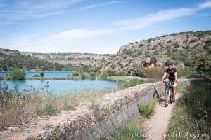 Hombre en bicicleta por un sendero con el paisaje de las Lagunas de Ruidera de fondo