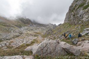 Cuatro montañeros caminando por un sendero pedregoso en los Pirineos