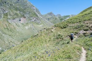 Hombre con un macuto a sus espaladas caminando por un sendero en mitad de los Pirineos