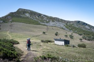 Hombre caminando hacia un refugio de montaña en la Sierra de Ancares