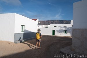 Hombre con mochila paseando por las calles sin asfaltar de Caleta de Sebo en La Graciosa (Islas Canarias)