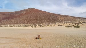Pareja en la playa con la Montaña Bermeja de fondo en La Graciosa