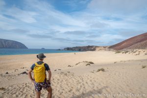 Hombre de espaldas en un paisaje de playa de arena dorada en La Graciosa