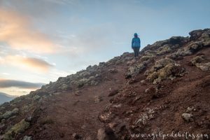 Mujer caminando por un sendero en la ladera de una montaña
