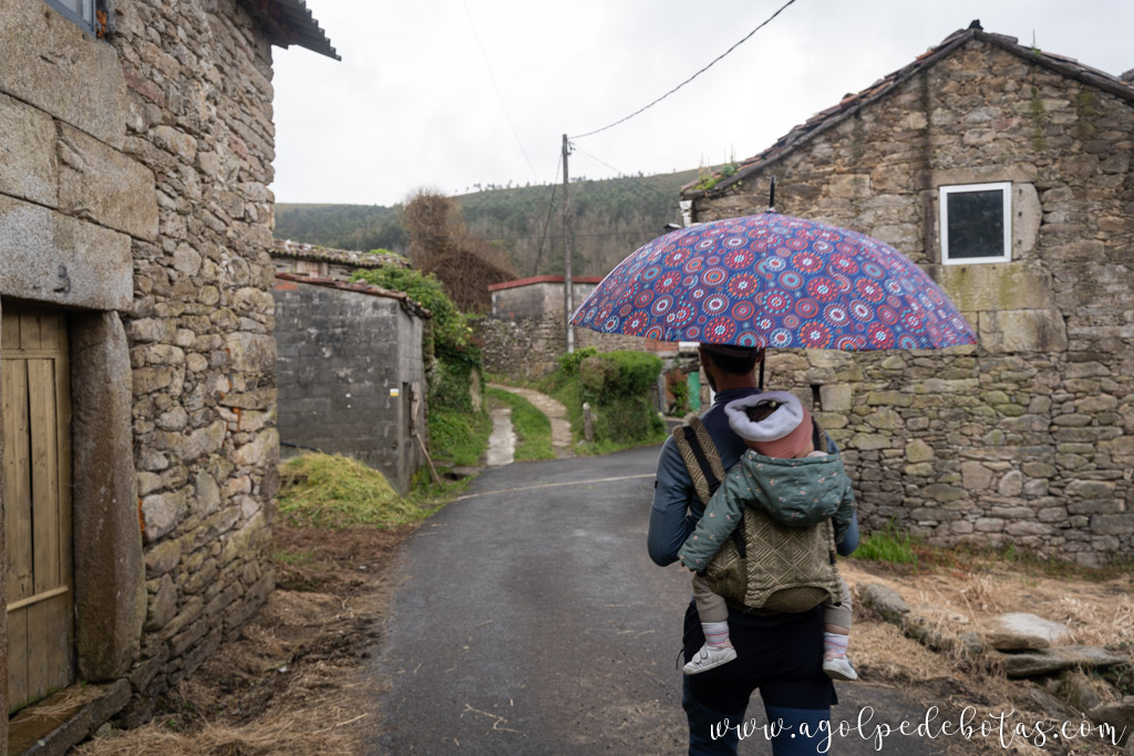 Hombre y bebé porteado paseando por la aldea de Parga durante la ruta del Agua de Zas en Galicia