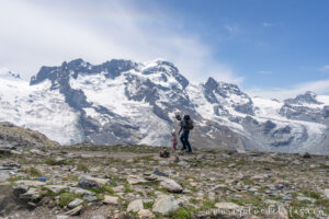 Padre e hija caminando en la montaña con los Alpes suizos de fondo