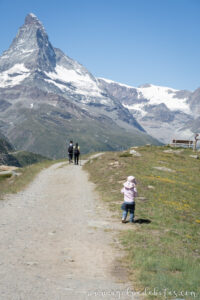 Niña caminando por un sendero de montaña con el Matterhorn de fondo