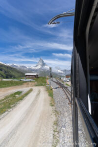 Tren panorámico subiendo hacia Gornergrat con vistas al Matterhorn desde la ventanilla, paisaje alpino en día despejado.